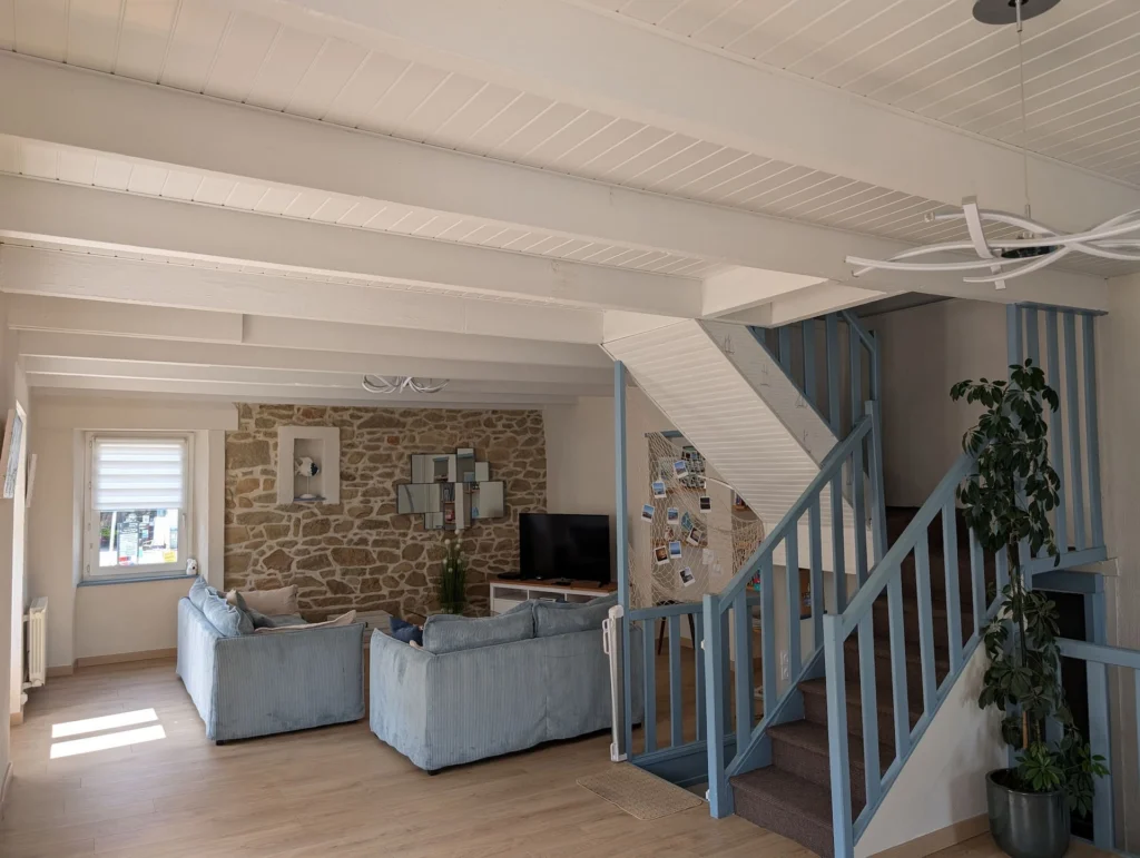 Le séjour, son mur en pierre et l'escalier vers les chambres